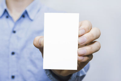 Close-up of human hand holding paper against white background