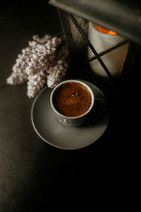 High angle view of coffee cup by lantern on table