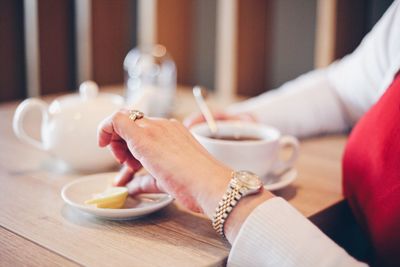 Cropped image of woman having coffee in cafe