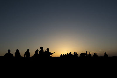 Silhouette people against clear sky during sunset