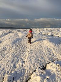 Rear view of woman walking on snow covered land