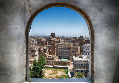 Buildings against sky seen through window