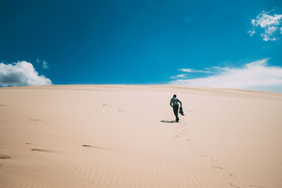 Man walking in desert against sky