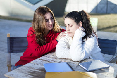 Young woman looking at camera while sitting on mobile phone