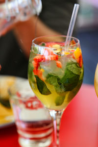 Close-up of tasty drink with strawberries and fresh herbs in glass on table