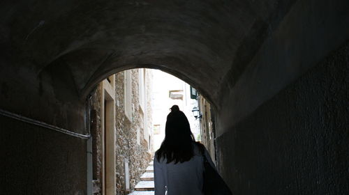 Rear view of woman standing against wall in building