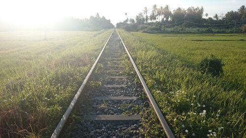 Railroad track amidst field against sky