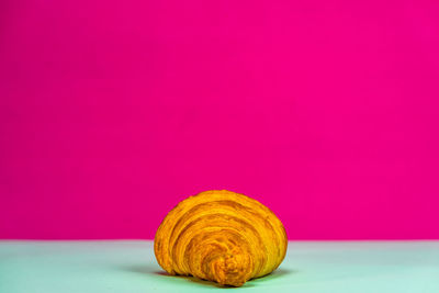 Close-up of bread on pink table against red background