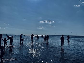 People enjoying at beach against sky