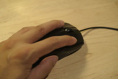 Cropped image of hand using computer mouse on table