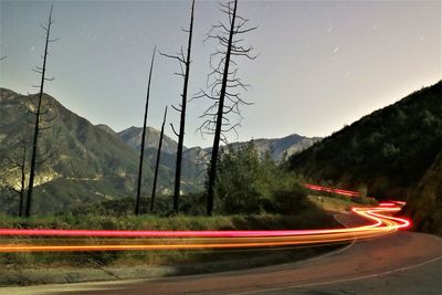 Light trails on road against clear sky