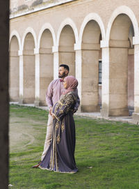 Husband with pregnant wife standing in park