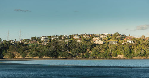 Scenic view of sea by townscape against sky