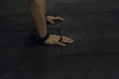 Cropped hands of man doing push-ups on floor at gym