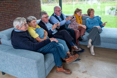 Friends using phone while sitting on sofa at home