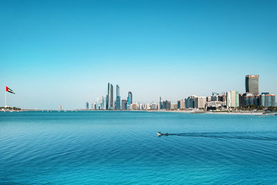 Scenic view of sea and buildings against clear blue sky