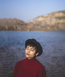 Portrait of an aesthetic looking girl wearing red sweater or sweatshirt with a black hat.