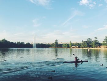 Man canoeing in lake against sky