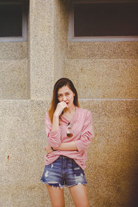 Portrait of smiling woman standing against wall