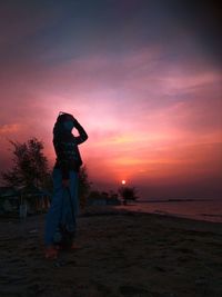 Silhouette woman photographing against orange sky