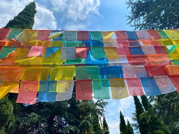 Low angle view of multi colored flags hanging against sky