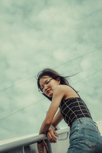 Portrait of young woman standing against sky