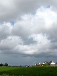 Scenic view of grassy field against cloudy sky