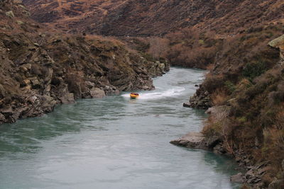 Drone shot of people rafting in river amidst mountain