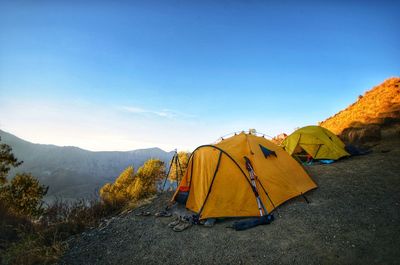 Yellow tent on mountain against clear sky