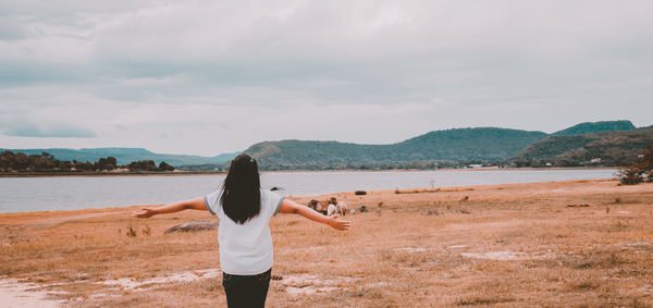 Rear view of woman walking on beach against sky