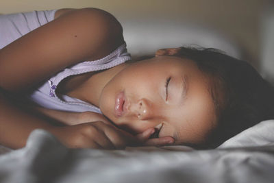Close-up of girl sleeping on bed at home