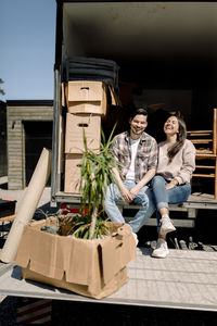 Portrait of happy couple sitting in delivery truck during sunny day