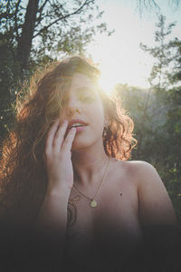 Portrait of young woman standing by tree