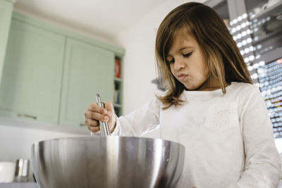 Low angle view of girl preparing food in kitchen