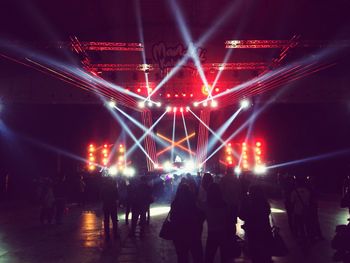 People at illuminated concert against sky at night