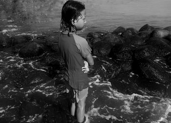 Girl standing on rock at sea shore