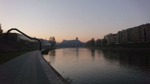 Bridge over river in city against clear sky during sunset