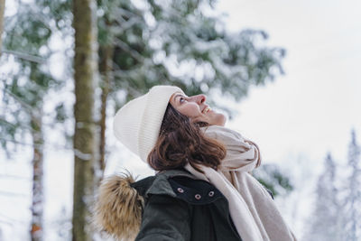 Woman wearing hat against trees during winter