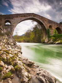 Arch bridge over river against sky