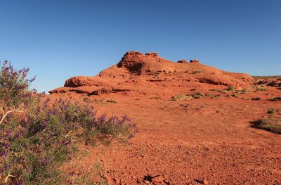 Rock formations on landscape against clear blue sky