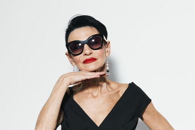 Portrait of young woman wearing sunglasses against white background