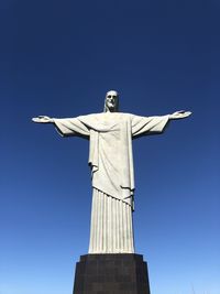 Low angle view of jesus statue against clear blue sky