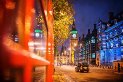 Car passing by illuminated buildings