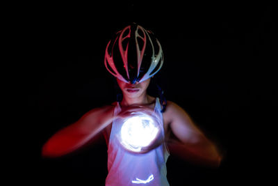 Midsection of man holding ball while standing against black background
