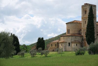 Old building by trees on field against sky