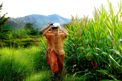 Boys walking amidst plants on field