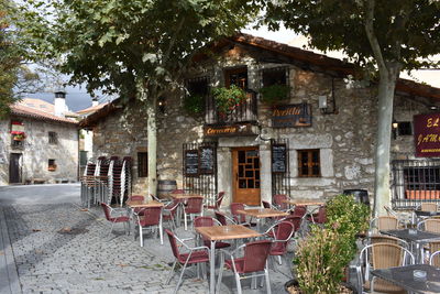 Chairs and tables at sidewalk cafe outside building