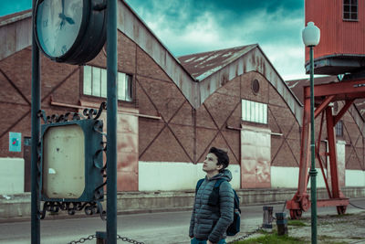 Young man looking at old clock in city