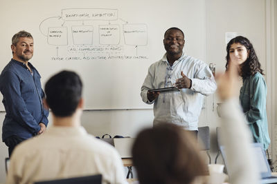 Male teacher with students doing q and a session in classroom