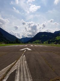 Road by mountains against sky